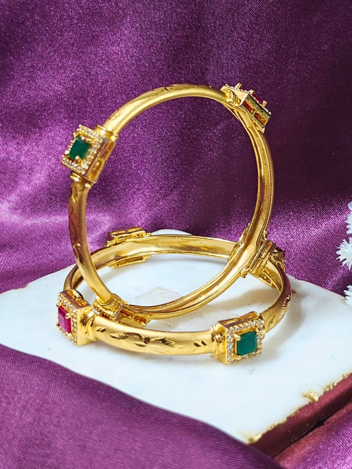 Close-up of an ornate traditional (Gold Polish) Bangles Set with American Diamond and Pink & Green Colored Stone. Festive celebration look enhanced with artificial Colored Stone bangles. Close-up of premium imitation Colored Stone bangles styled with a silk saree.