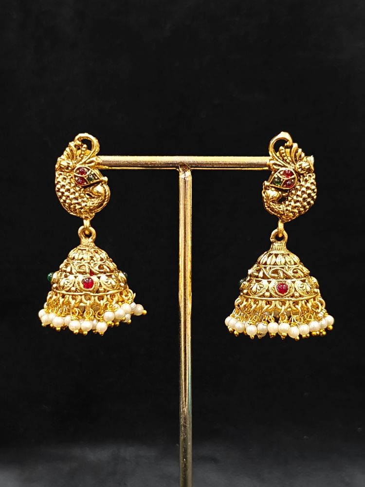 The Vidya Temple Necklace Set featuring a traditional gold Long necklace and matching earrings with Goddess Laxmi in the middle, along with pink and green colored stones, Pearls and Mehendi Polish. Wedding guest look completed with a temple necklace set. Close-up of detailed temple carvings in artificial wedding jewelry.