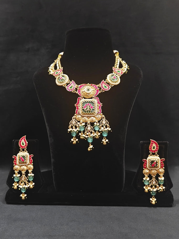 Close-up of an ornate traditional (Gold Polish) Pink & Mint Green Collar jewellery set and earrings and with Enamel and Pearls. Wedding celebration look featuring a premium heritage artificial set. Woman wearing a heritage-style artificial necklace for long wedding functions.
