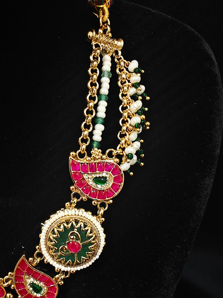 Close-up of an ornate traditional (Gold Polish) Pink & Mint Green Collar jewellery set and earrings and with Enamel and Pearls. Wedding celebration look featuring a premium heritage artificial set. Woman wearing a heritage-style artificial necklace for long wedding functions.