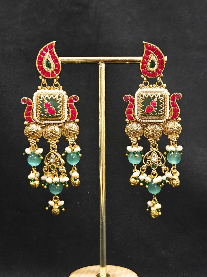 Close-up of an ornate traditional (Gold Polish) Pink & Mint Green Collar jewellery set and earrings and with Enamel and Pearls. Wedding celebration look featuring a premium heritage artificial set. Woman wearing a heritage-style artificial necklace for long wedding functions.