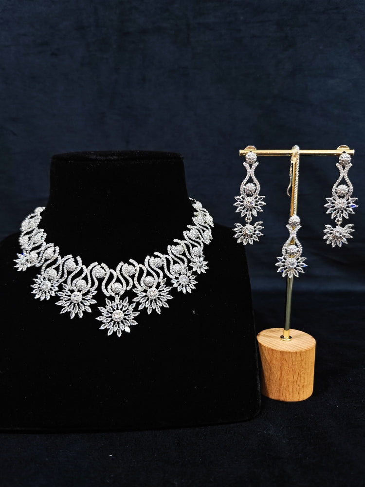 Close-up of an ornate Indo-western American Diamond Silver Collar jewellery set and earrings and maangtikka with American Diamond. A woman wearing a luxury American diamond necklace set styled beautifully for a wedding guest look in India. Reception-ready look featuring a statement American diamond jewelry set.