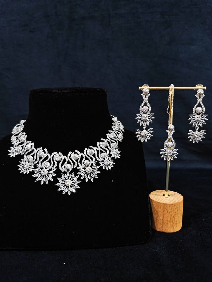 Close-up of an ornate Indo-western American Diamond Silver Collar jewellery set and earrings and maangtikka with American Diamond. A woman wearing a luxury American diamond necklace set styled beautifully for a wedding guest look in India. Reception-ready look featuring a statement American diamond jewelry set.