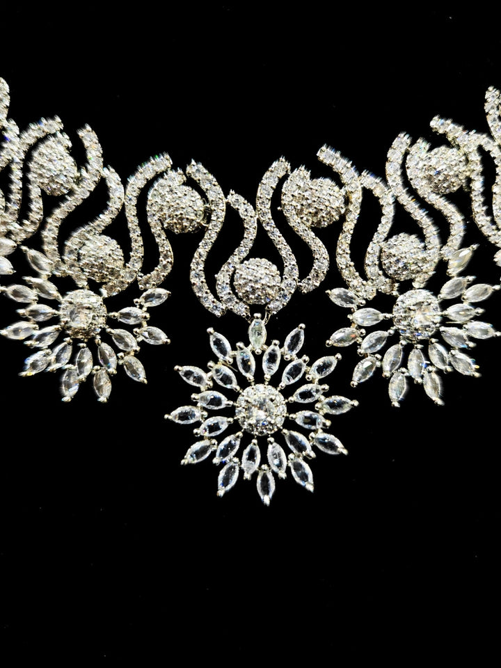 Close-up of an ornate Indo-western American Diamond Silver Collar jewellery set and earrings and maangtikka with American Diamond. A woman wearing a luxury American diamond necklace set styled beautifully for a wedding guest look in India. Reception-ready look featuring a statement American diamond jewelry set.