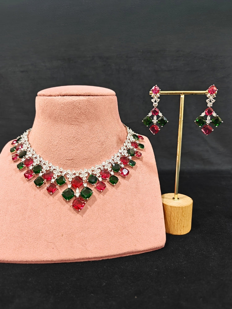 An exquisite artificial diamond and red and green colored stone necklace and matching earrings, designed for the perfect engagement look. This stunning artificial diamond jewelry set offers luxury and sophistication while being an affordable alternative to natural diamonds.