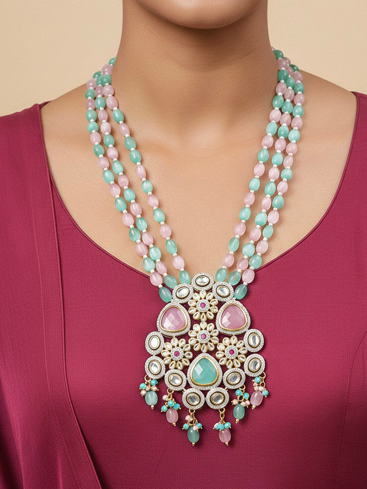 Close-up of a woman wearing an ornate traditional Mint Green and Pink Long jewellery set and earrings with American Diamond, Kundan, Tumble & Crystal Beads, Pearls, Tyaani Kundan and Monalisa Stone. Woman wearing trending Colored Stone artificial jewelry for wedding season in India. Festive saree styling with a premium artificial Colored Stone necklace.