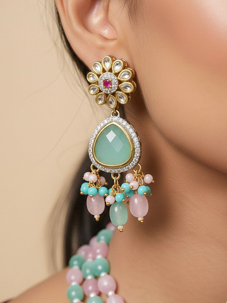 Close-up of a woman wearing an ornate traditional Mint Green and Pink Long jewellery set and earrings with American Diamond, Kundan, Tumble & Crystal Beads, Pearls, Tyaani Kundan and Monalisa Stone. Woman wearing trending Colored Stone artificial jewelry for wedding season in India. Festive saree styling with a premium artificial Colored Stone necklace.