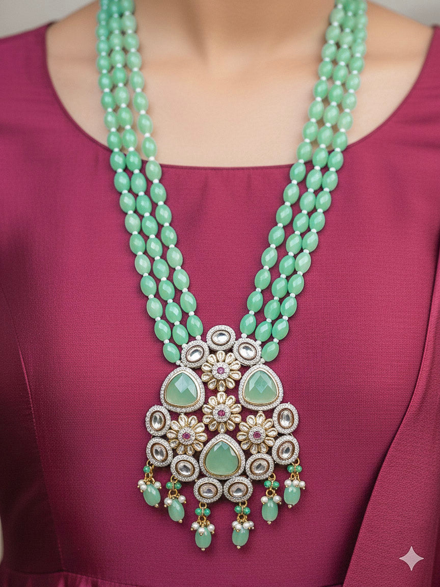 Close-up of a woman wearing an ornate traditional Sea Green Long jewellery set and earrings with American Diamond, Kundan, Tumble & Crystal Beads, Pearls, Tyaani Kundan and Monalisa Stone. Woman wearing trending Colored Stone artificial jewelry for wedding season in India. Festive saree styling with a premium artificial Colored Stone necklace.