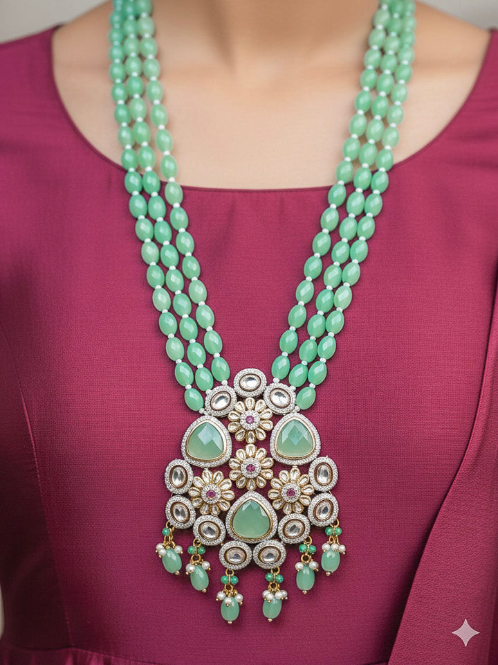 Close-up of a woman wearing an ornate traditional Sea Green Long jewellery set and earrings with American Diamond, Kundan, Tumble & Crystal Beads, Pearls, Tyaani Kundan and Monalisa Stone. Woman wearing trending Colored Stone artificial jewelry for wedding season in India. Festive saree styling with a premium artificial Colored Stone necklace.