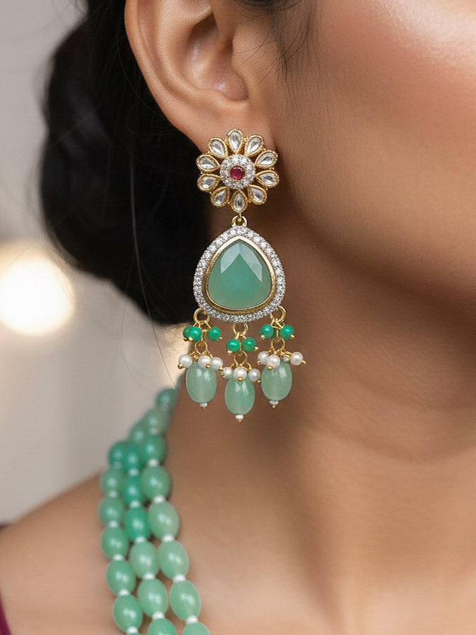 Close-up of a woman wearing an ornate traditional Sea Green Long jewellery set and earrings with American Diamond, Kundan, Tumble & Crystal Beads, Pearls, Tyaani Kundan and Monalisa Stone. Woman wearing trending Colored Stone artificial jewelry for wedding season in India. Festive saree styling with a premium artificial Colored Stone necklace.