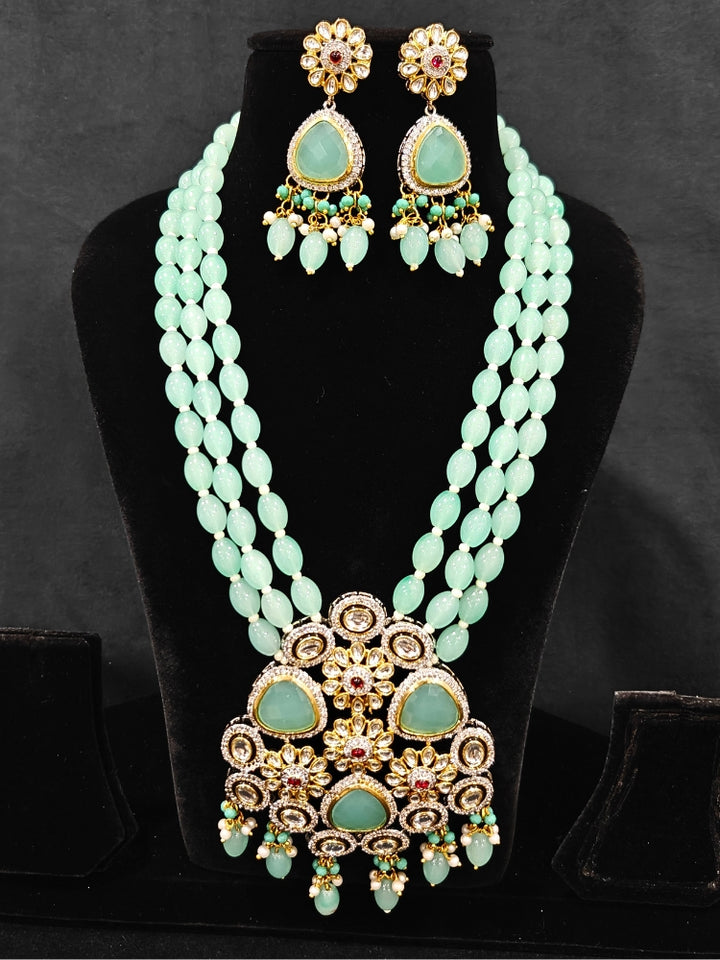 Close-up of  an ornate traditional Sea Green Long jewellery set and earrings with American Diamond, Kundan, Tumble & Crystal Beads, Pearls, Tyaani Kundan and Monalisa Stone. A trending Colored Stone artificial jewelry for wedding season in India. Festive saree styling with a premium artificial Colored Stone necklace.