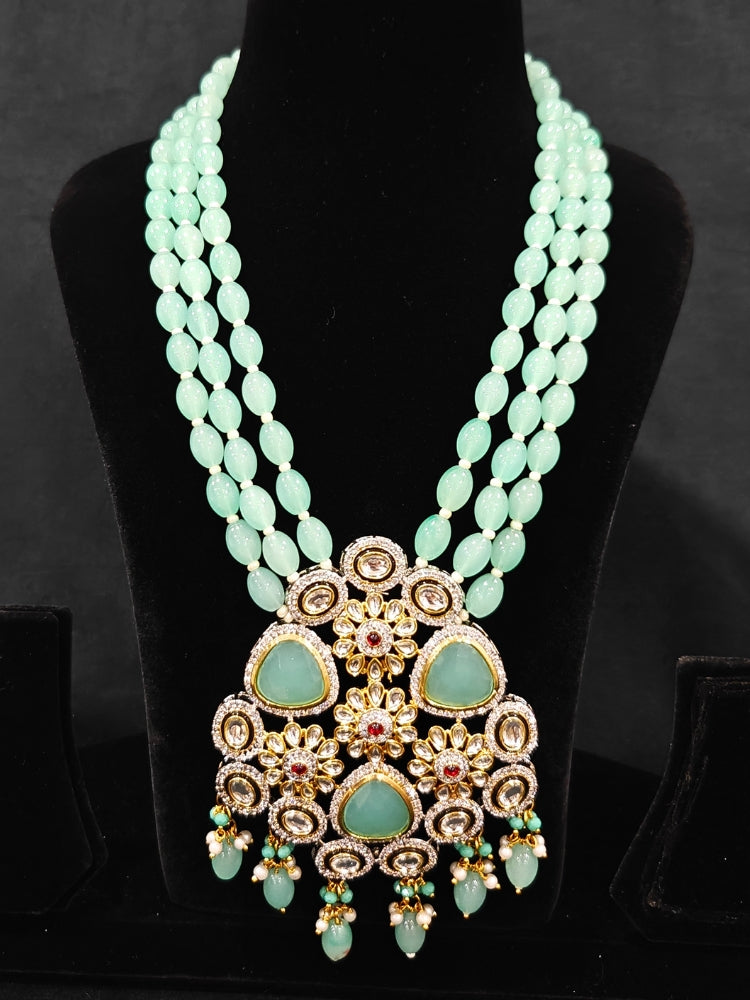 Close-up of  an ornate traditional Sea Green Long jewellery set and earrings with American Diamond, Kundan, Tumble & Crystal Beads, Pearls, Tyaani Kundan and Monalisa Stone. A trending Colored Stone artificial jewelry for wedding season in India. Festive saree styling with a premium artificial Colored Stone necklace.