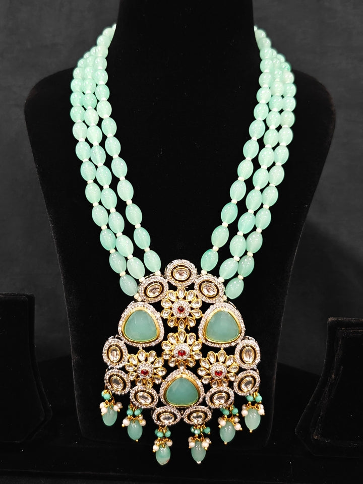 Close-up of  an ornate traditional Sea Green Long jewellery set and earrings with American Diamond, Kundan, Tumble & Crystal Beads, Pearls, Tyaani Kundan and Monalisa Stone. A trending Colored Stone artificial jewelry for wedding season in India. Festive saree styling with a premium artificial Colored Stone necklace.