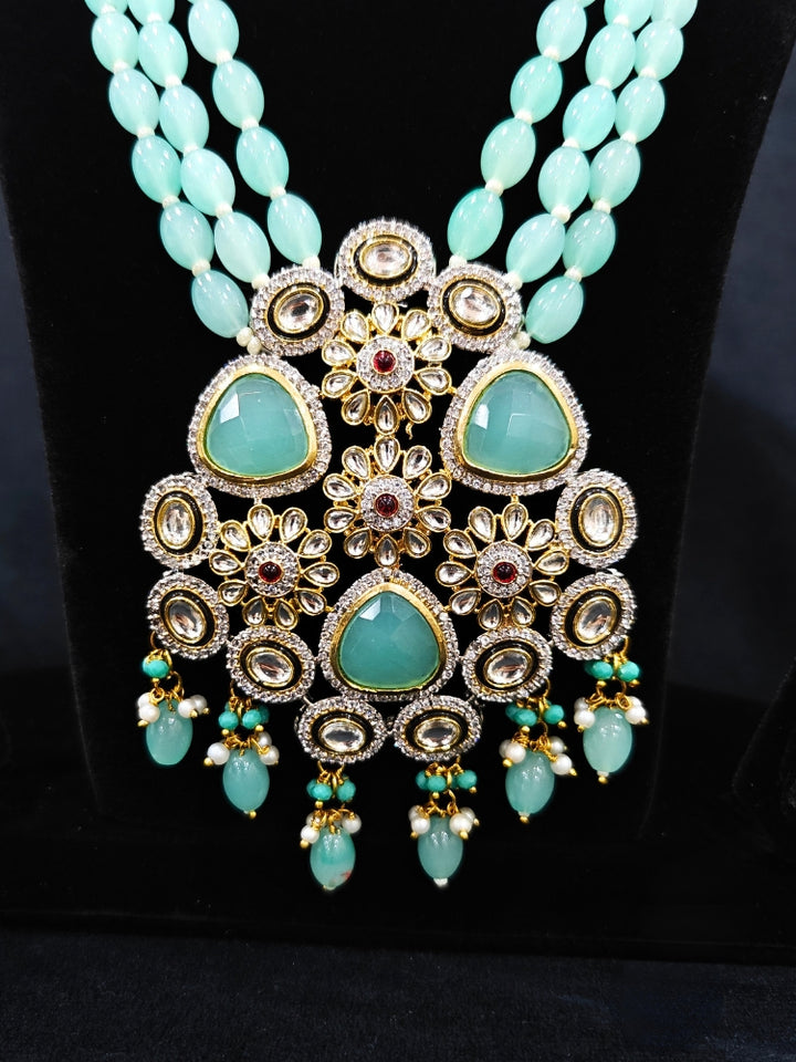 Close-up of  an ornate traditional Sea Green Long jewellery set and earrings with American Diamond, Kundan, Tumble & Crystal Beads, Pearls, Tyaani Kundan and Monalisa Stone. A trending Colored Stone artificial jewelry for wedding season in India. Festive saree styling with a premium artificial Colored Stone necklace.