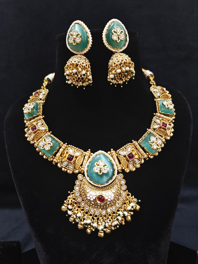 Close-up of an ornate traditional Mint Green Heritage gold Collar jewellery set and earrings with Mint Green Colored Stones, Kundan and Pearls. Woman styling a vintage heritage artificial necklace for a reception party. Perfect  Heritage necklace set for weddings and festivals.
