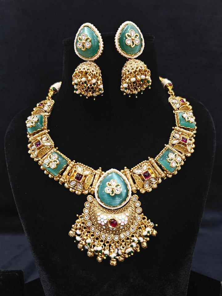 Close-up of an ornate traditional Mint Green Heritage gold Collar jewellery set and earrings with Mint Green Colored Stones, Kundan and Pearls. Woman styling a vintage heritage artificial necklace for a reception party. Perfect  Heritage necklace set for weddings and festivals.
