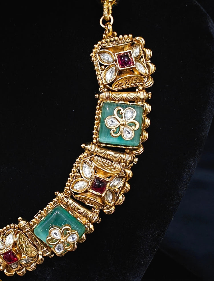 Close-up of an ornate traditional Mint Green Heritage gold Collar jewellery set and earrings with Mint Green Colored Stones, Kundan and Pearls. Woman styling a vintage heritage artificial necklace for a reception party. Perfect  Heritage necklace set for weddings and festivals.