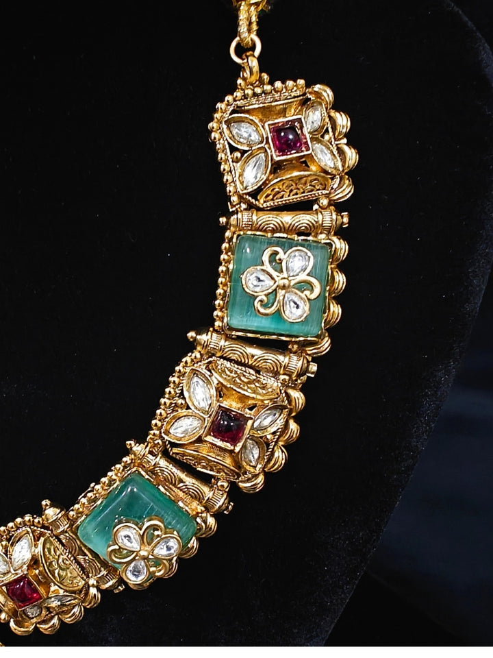 Close-up of an ornate traditional Mint Green Heritage gold Collar jewellery set and earrings with Mint Green Colored Stones, Kundan and Pearls. Woman styling a vintage heritage artificial necklace for a reception party. Perfect  Heritage necklace set for weddings and festivals.