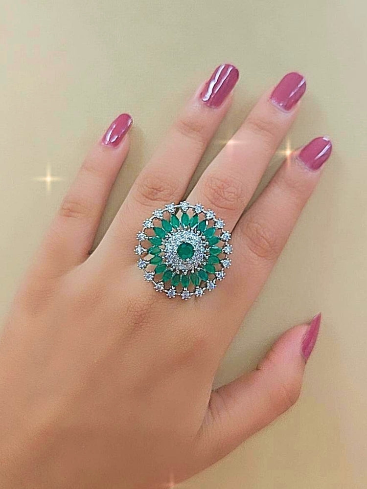 The Wallace Green Ring features a circular design with a central Green gemstone, surrounded by American diamonds and marquise-shaped Green stones, set against a Green and white background adorned with roses. Perfect American Diamond cocktail ring. 