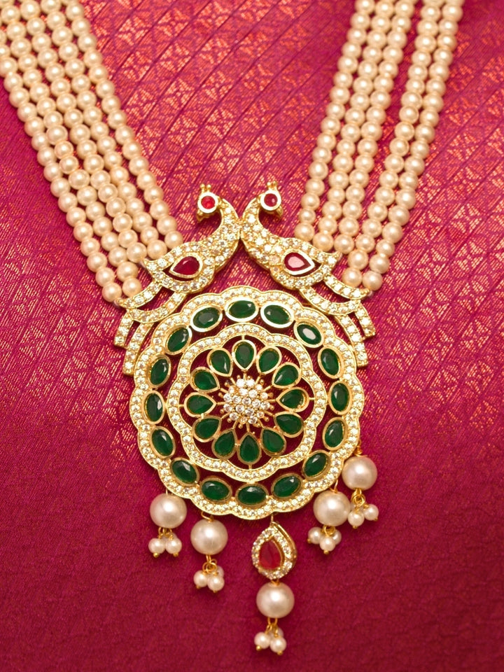 Close-up of a woman wearing an ornate traditional (Gold Polish) White Long Jewellery Set and Earrings with Colored Stones, Pearl and American Dimaonds.  Wedding guest wearing a lightweight Kundan necklace for a Wedding function. Woman wearing trending Pearl artificial jewelry for wedding season in India.