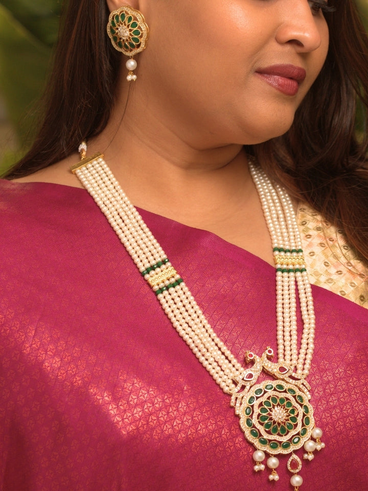 Close-up of a woman wearing an ornate traditional (Gold Polish) White Long Jewellery Set and Earrings with Colored Stones, Pearl and American Dimaonds.  Wedding guest wearing a lightweight Kundan necklace for a Wedding function. Woman wearing trending Pearl artificial jewelry for wedding season in India.