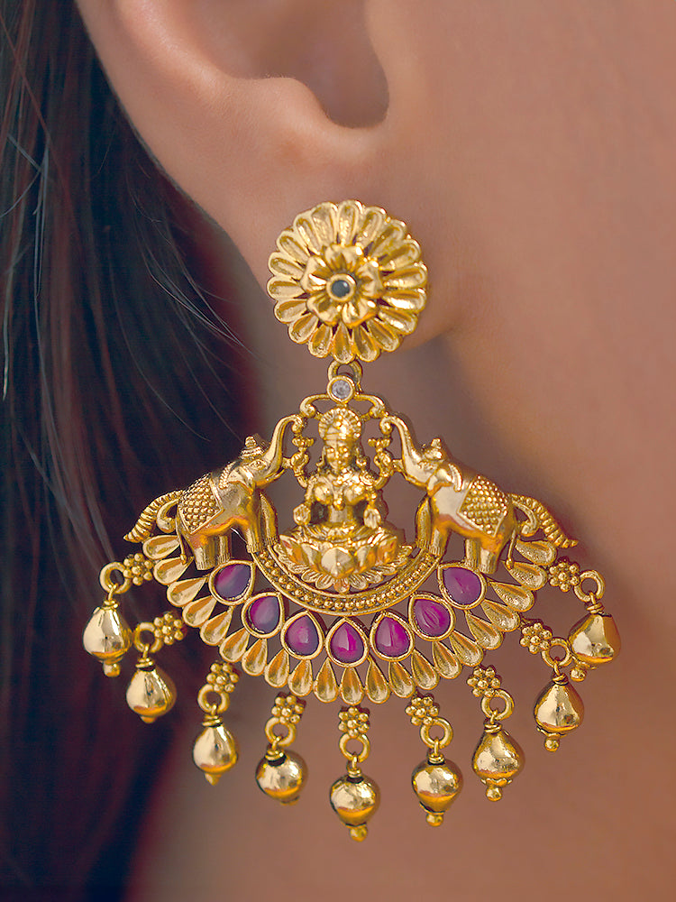 A woman wearing the Yagnika Choker Necklace Set featuring a traditional gold choker necklace and matching chandbali earrings with Goddess Laxmi in the middle, along with pink and green colored stones, golden elephants at the corners, paired with a pink and gold blouse—ideal party jewelry for any festive occasion.