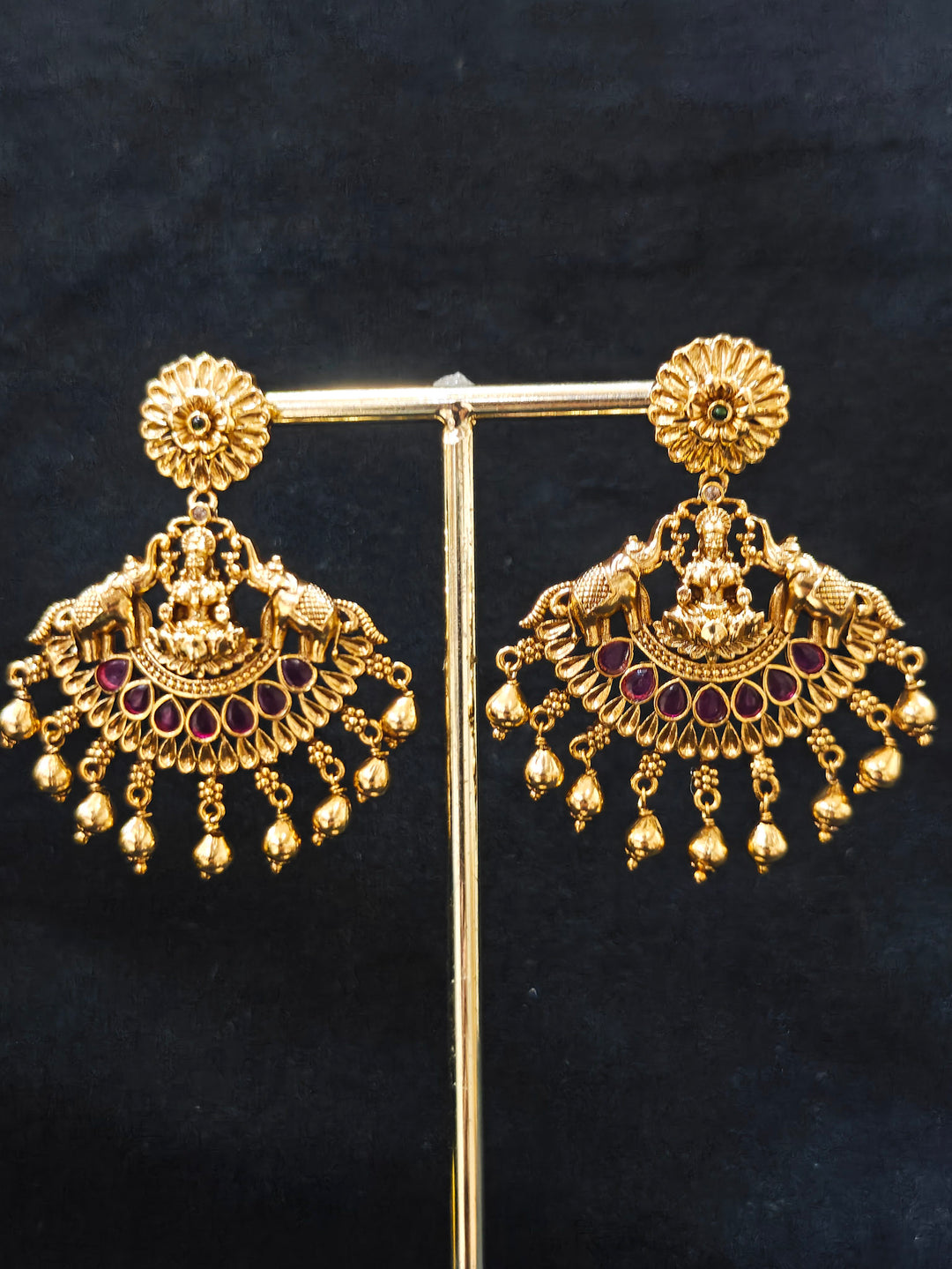 The Yagnika Choker Necklace Set featuring a traditional gold choker necklace and matching chandbali earrings with Goddess Laxmi in the middle, along with pink and green colored stones, golden elephants at the corners, paired with a pink and gold blouse—ideal party jewelry for any festive occasion.