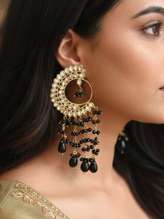 Close-up of a woman wearing an ornate traditional (Gold Polish) Black Long  Earrings with Kundan and Black Beads. Mehendi ceremony look completed with a handcrafted Kundan Earrings. Wedding celebration look enhanced with a statement Kundan Earrings.