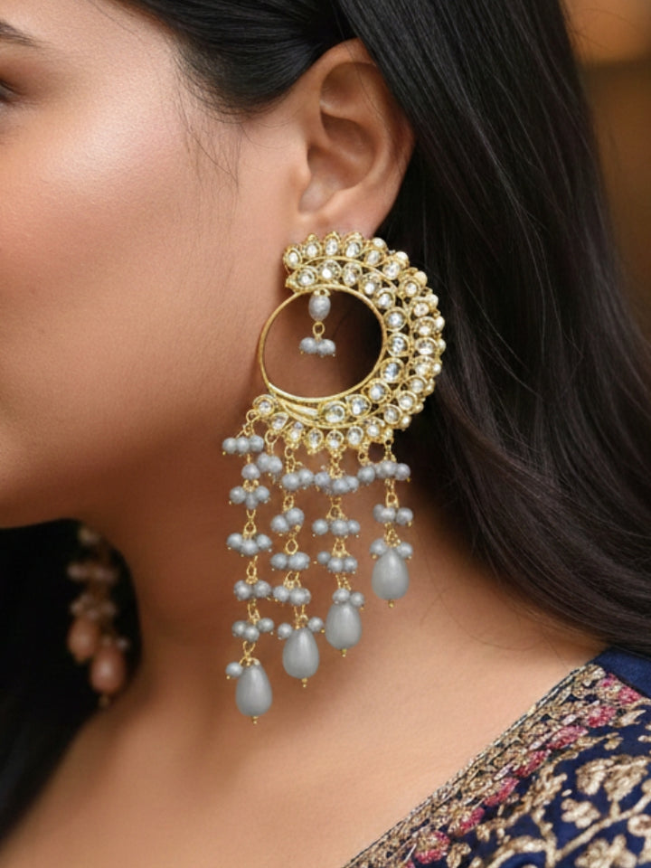 Close-up of a woman wearing an ornate traditional (Gold Polish) Grey Long  Earrings with Kundan and Grey Beads. Mehendi ceremony look completed with a handcrafted Kundan Earrings. Wedding celebration look enhanced with a statement Kundan Earrings.