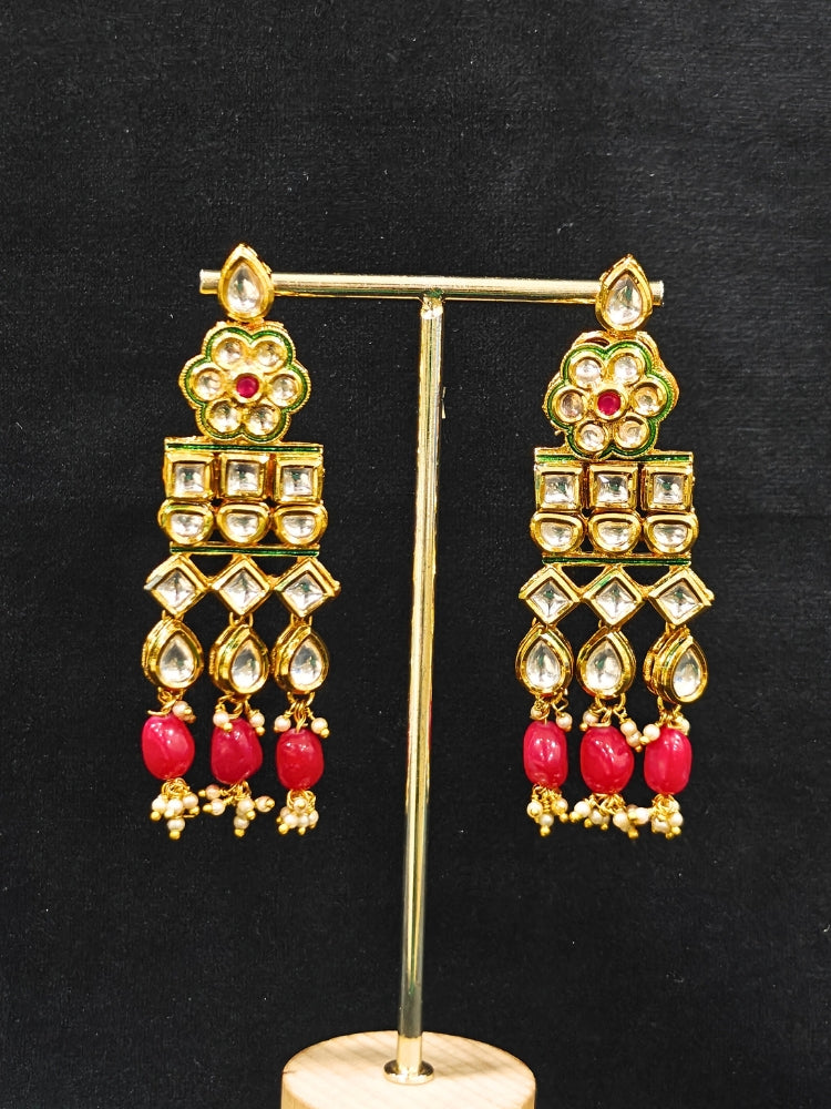 Close-up of an ornate traditional (Gold Polish) White Long jewellery set and earrings with Kundan, Red Colored Stone and Red Beads. Woman wearing trending Kundan artificial jewelry for wedding season in India. Wedding guest wearing a lightweight Kundan necklace for a festive function.