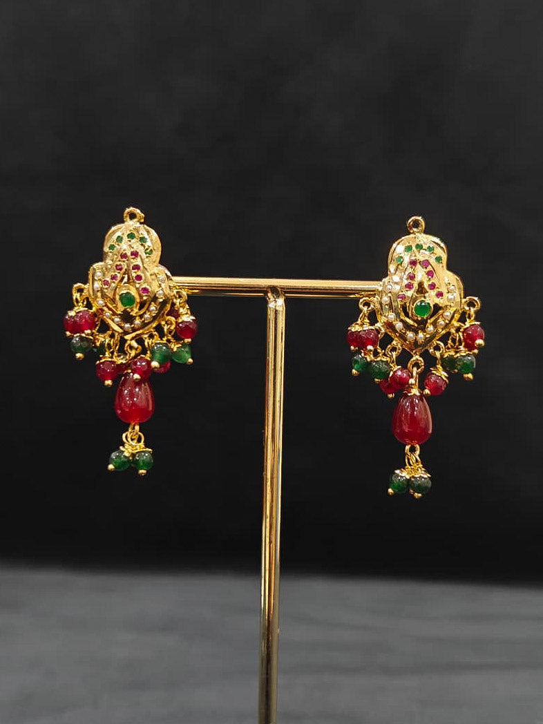 Close-up of an ornate traditional Maroon and Dark Green jadau gold Pendant set and jadau earrings with pearls, Beads and Color Stone. Elegant  look featuring a luxury Jadau artificial Pendant set. Festive celebration look featuring a Jadau artificial Pendant Set.