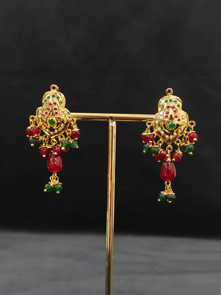 Close-up of an ornate traditional Maroon and Dark Green jadau gold Pendant set and jadau earrings with pearls, Beads and Color Stone. Elegant  look featuring a luxury Jadau artificial Pendant set. Festive celebration look featuring a Jadau artificial Pendant Set.