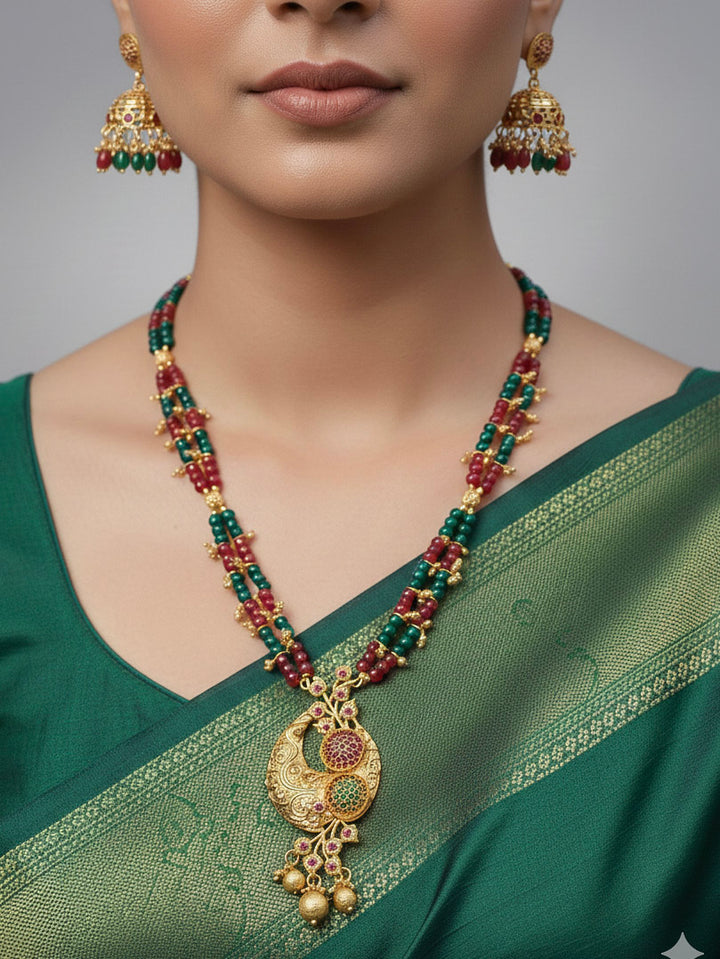 Close-up of a woman wearing an ornate traditional (Gold Polish) Red & Green Jewellery Set and Earrings with Red and Green Colored Stone and Colored Beads. Mehendi ceremony look completed with a Colored Stone Necklace Set. Festive celebration look enhanced with traditional Colored Stone jewelry.