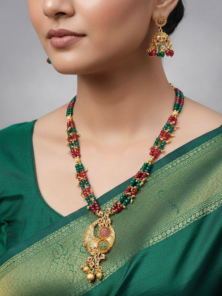 Close-up of a woman wearing an ornate traditional (Gold Polish) Red & Green Jewellery Set and Earrings with Red and Green Colored Stone and Colored Beads. Mehendi ceremony look completed with a Colored Stone Necklace Set. Festive celebration look enhanced with traditional Colored Stone jewelry.