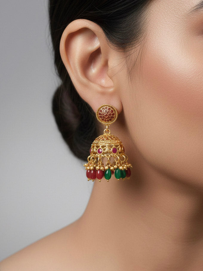 Close-up of a woman wearing an ornate traditional (Gold Polish) Red & Green Jewellery Set and Earrings with Red and Green Colored Stone and Colored Beads. Mehendi ceremony look completed with a Colored Stone Necklace Set. Festive celebration look enhanced with traditional Colored Stone jewelry.