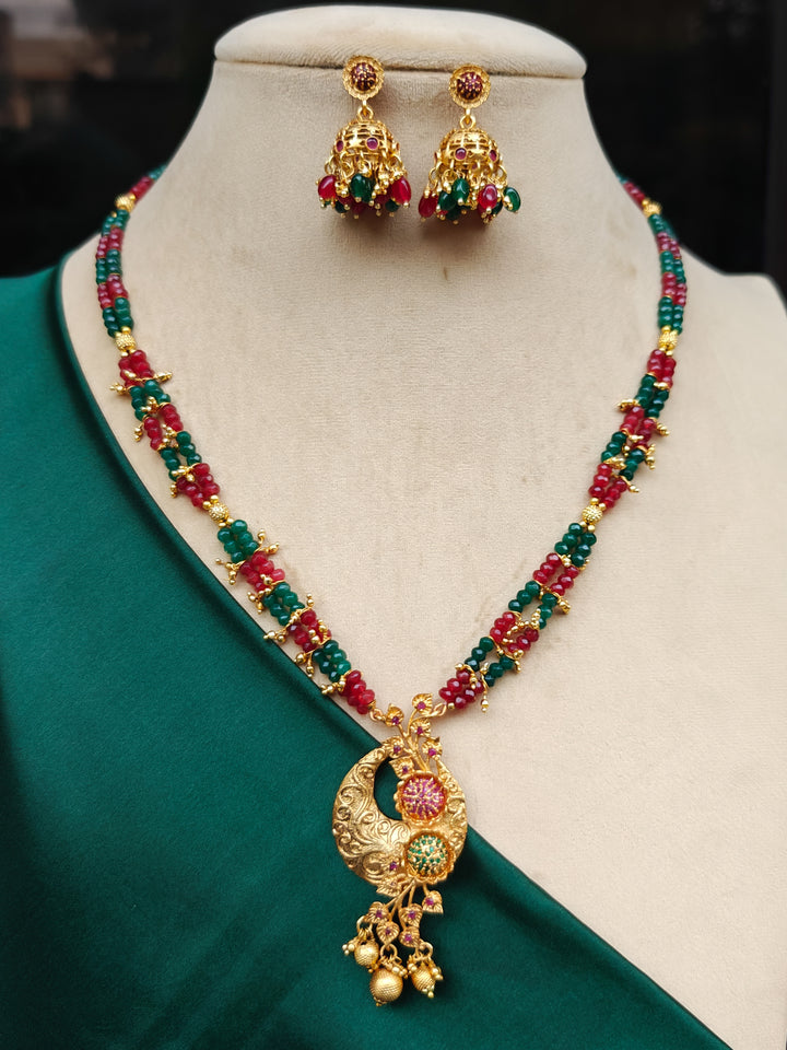 Close-up of an ornate traditional (Gold Polish) Red & Green Jewellery Set and Earrings with Red and Green Colored Stone and Colored Beads. Mehendi ceremony look completed with a Colored Stone Necklace Set. Festive celebration look enhanced with traditional Colored Stone jewelry.