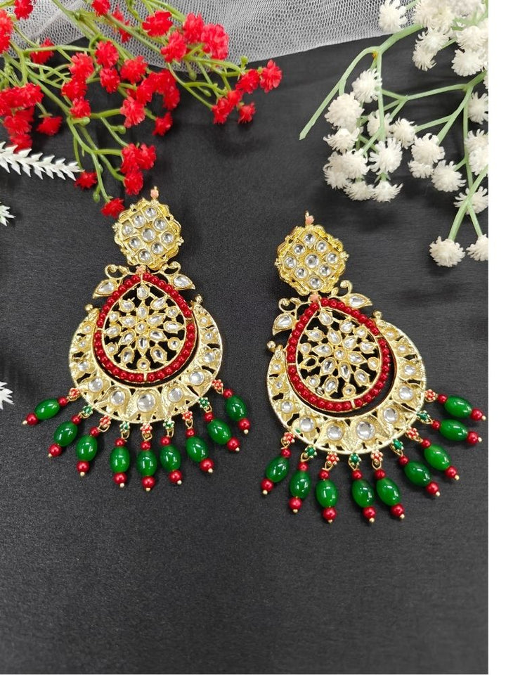 Close-up of an ornate traditional Green Long Kundan Earrings with Kundan, Red/Green Beads and Tumble Beads. A statement artificial Kundan earrings for a wedding guest look in India. A long bridal artificial Kundan earrings for a traditional wedding. Perfect Kundan Earrings for Wedding Functions and Festive.