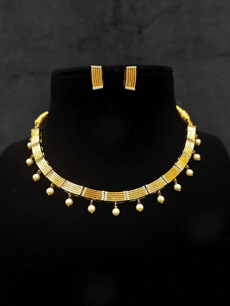 Close-up of an ornate traditional (Gold Polish) Collar jewellery set and earrings with American Diamond and Pearl. Festive saree styling completed with an elegant artificial Pearl jewelry piece. Festive party wear look featuring a Collar Pearl artificial jewelry piece.