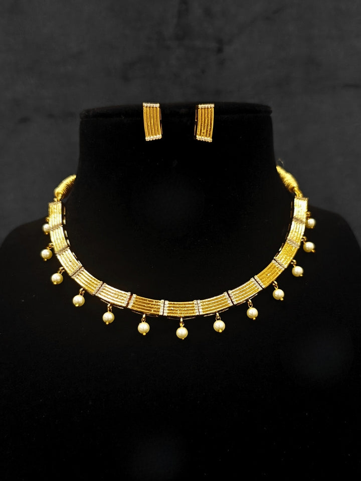 Close-up of an ornate traditional (Gold Polish) Collar jewellery set and earrings with American Diamond and Pearl. Festive saree styling completed with an elegant artificial Pearl jewelry piece. Festive party wear look featuring a Collar Pearl artificial jewelry piece.
