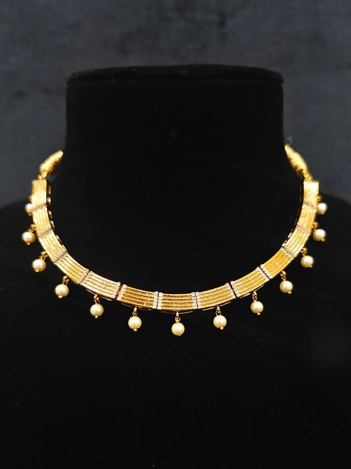 Close-up of an ornate traditional (Gold Polish) Collar jewellery set and earrings with American Diamond and Pearl. Festive saree styling completed with an elegant artificial Pearl jewelry piece. Festive party wear look featuring a Collar Pearl artificial jewelry piece.