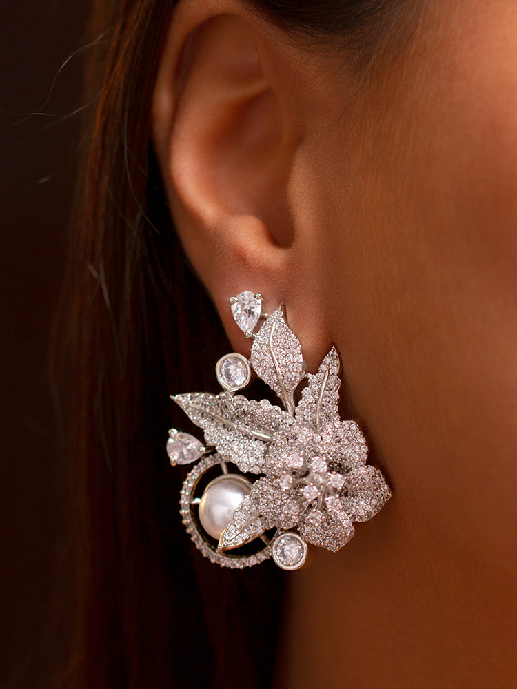 Close-up of a woman wearing an ornate  Western (Silver Polish) Diamond Earrings with American Diamond and Pearl. Reception-ready look featuring a statement American diamond Earring. Close-up of a cocktail party look featuring a premium American diamond Earrings.