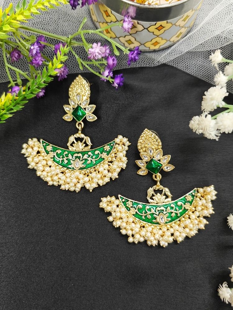 Close-up of an ornate traditional Green Meenakari gold Earrings with Pearls, Kundan and Meenakari. Mehendi ceremony look completed with a handcrafted Meenakari Earrings. Close-up of detailed enamel craftsmanship in Meenakari Earrings.