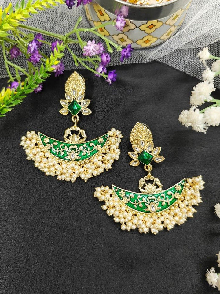 Close-up of an ornate traditional Green Meenakari gold Earrings with Pearls, Kundan and Meenakari. Mehendi ceremony look completed with a handcrafted Meenakari Earrings. Close-up of detailed enamel craftsmanship in Meenakari Earrings.