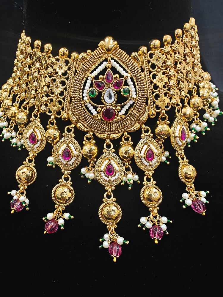 Close-up of an ornate traditional (Bright Gold Polish) Choker jewellery set and earrings with Pearl and Colored Stone. Woman wearing a vibrant Colored Stone artificial jewelry set for celebrations. Wedding function styling with a premium Colored Stone imitation necklace.