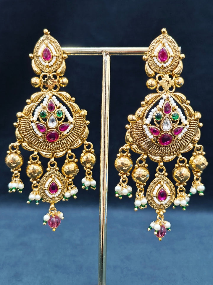 Close-up of an ornate traditional (Bright Gold Polish) Choker jewellery set and earrings with Pearl and Colored Stone. Woman wearing a vibrant Colored Stone artificial jewelry set for celebrations. Wedding function styling with a premium Colored Stone imitation necklace.