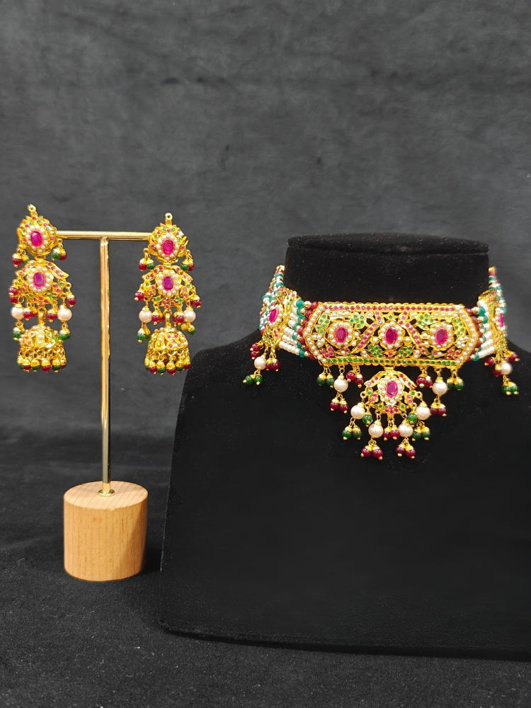 Close-up of a woman wearing an ornate traditional Choker jadau gold jewellery set and  jadau earrings with crystals beads and gemstones. Perfect Jadau necklace set for weddings and festivals. Elegant reception look featuring a luxury Jadau artificial jewelry set.