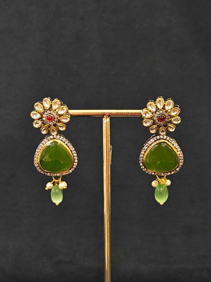 Close-up of an ornate traditional (Black Polish) Mehendi Green long jewellery set and earrings with Mehendi Green Colored Stones, Tumble Beads, Pearls and American Diamond. Woman wearing trending Colored Stone artificial jewelry for wedding season in India. Festive celebration look enhanced with traditional Colored Stone jewelry.