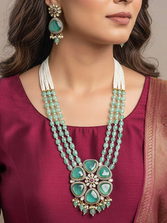 Close-up of a woman wearing an ornate traditional (Black Polish) Sea Green long jewellery set and earrings with Sea Green Colored Stones, Tumble Beads, Pearls and American Diamond. Woman wearing trending Colored Stone artificial jewelry for wedding season in India. Festive celebration look enhanced with traditional Colored Stone jewelry.