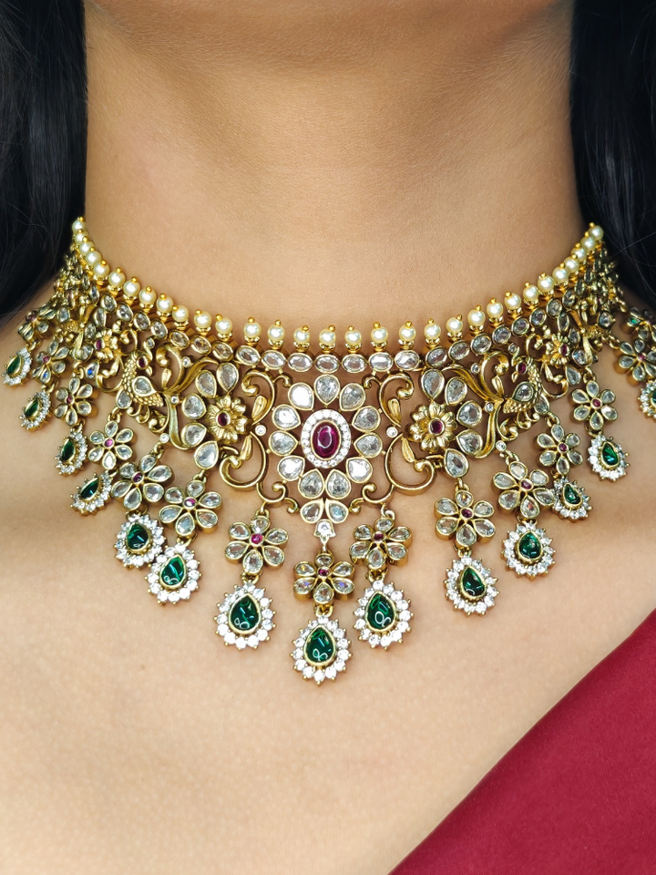 Gold AD choker necklace styled for a wedding guest look with red and green stones