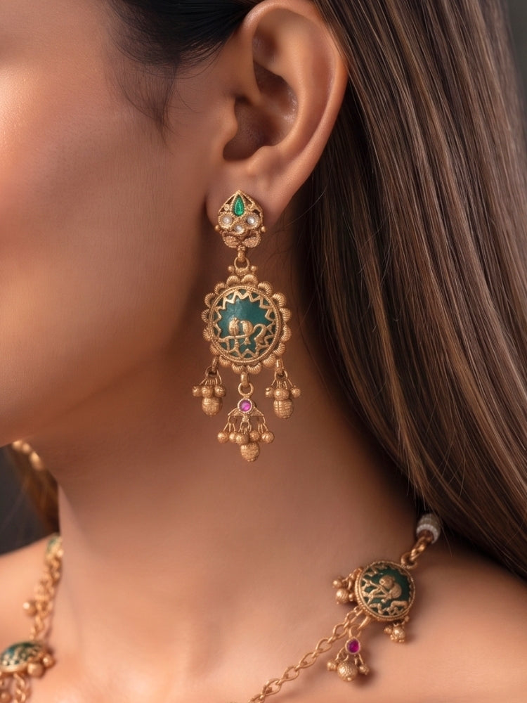 Long antique gold earrings with green bird-motif disc and ghungroo clusters